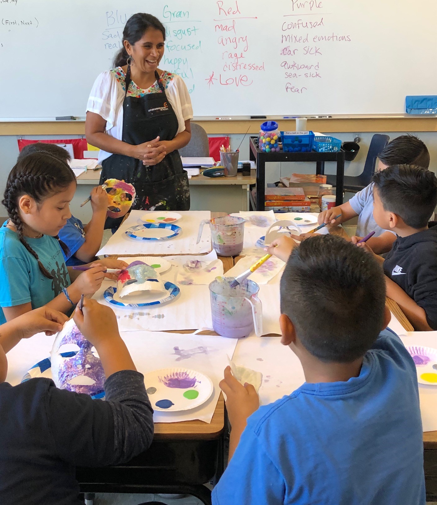 A teacher help students with masks that will relate their feelings. 